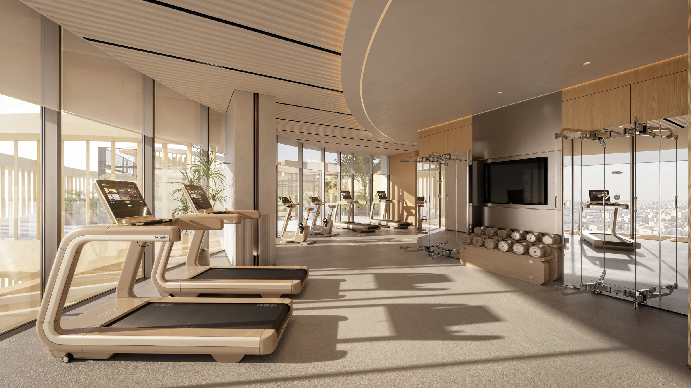 A gym with treadmills and weights facing tall windows