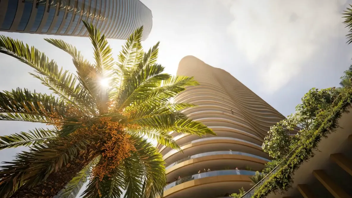 Burj Urubah seen from its garden, looking up past a palm against the sun
